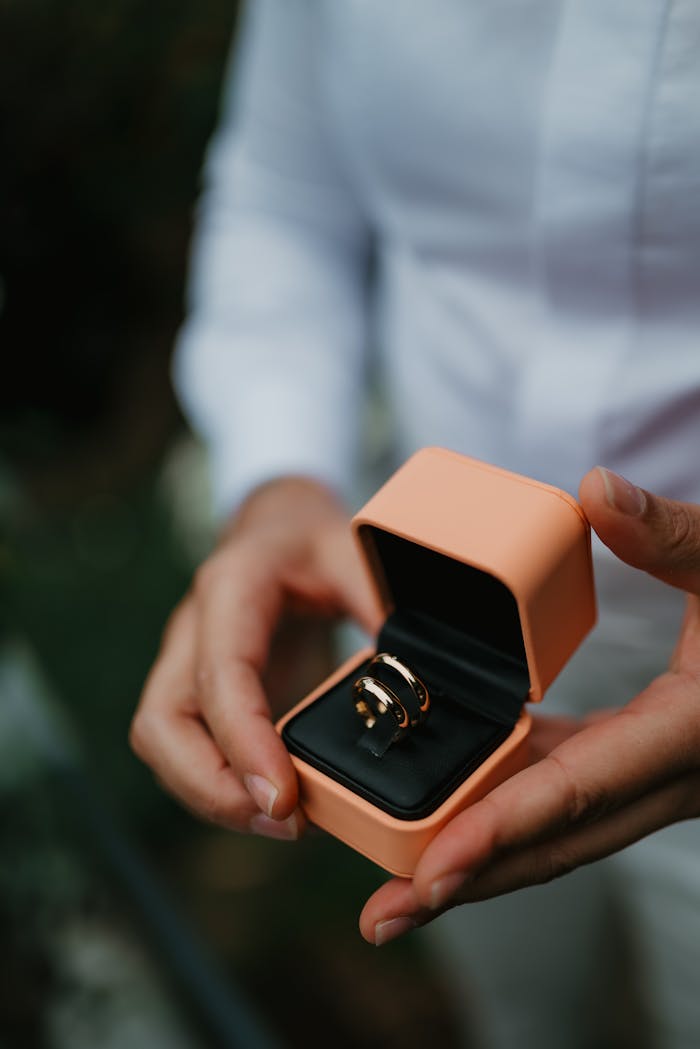 Close-up of hands holding an elegant ring in a box, perfect for engagements or gift ideas.
